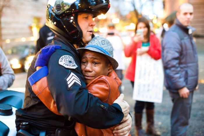 In this Tuesday, Nov. 25, 2014 photo provided by Johnny Nguyen, Portland police Sgt. Bret Barnum, left, and Devonte Hart, 12, hug at a rally in Portland, Ore., where people had gathered in support of the protests in Ferguson, Mo. (AP Photo/Johnny Huu Nguyen)